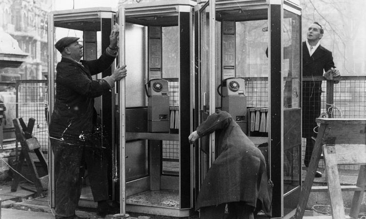 Tre uomini aggiustano le cabine telefoniche