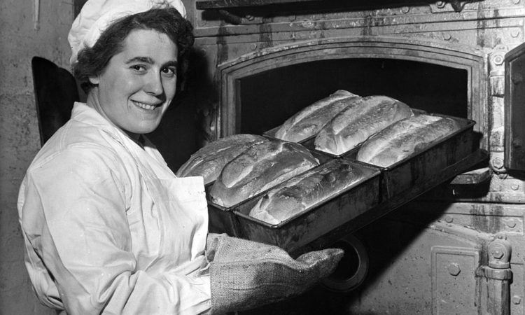 Una signora con una teglia di pane fra le mani