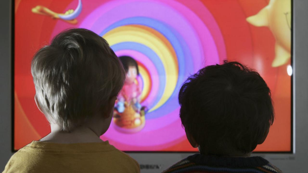 Due piccoli bambini di fronte a una tv