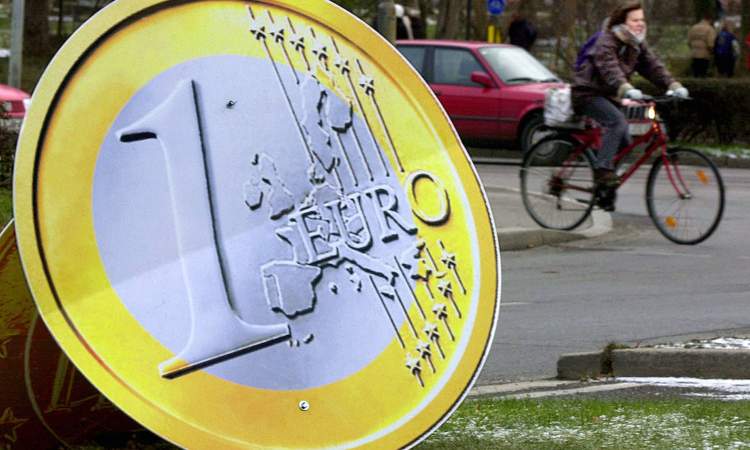 Una moneta da un euro in primo piano e una bicicletta sullo sfondo