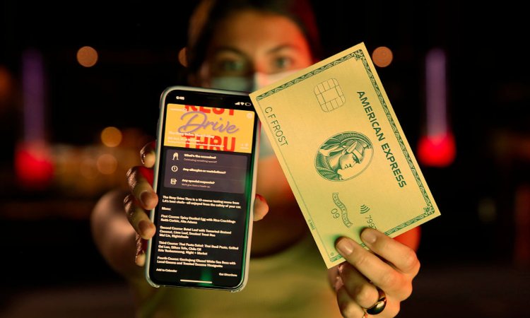 Una persona con in mano una finta carta di credito e uno smartphone 