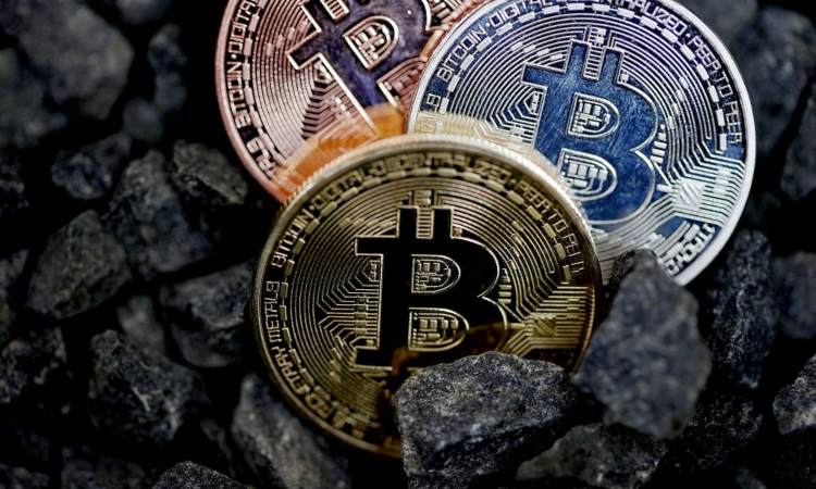 Tre monete dei BTC poggiate su dei sassi neri