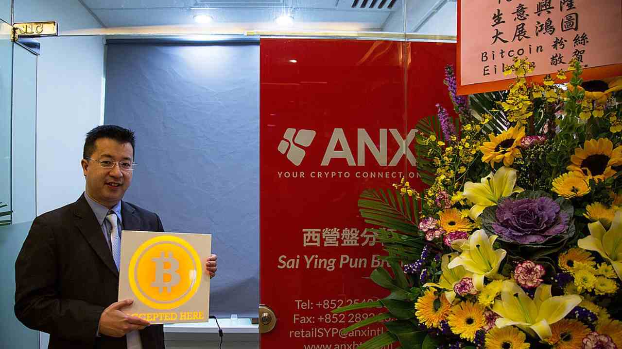 Ken Lo, CEO di ANX, posa sorridente con il simbolo dei Bitcoin fra le mani