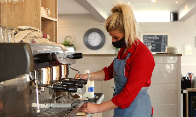 Una persona mentre fa un caffè alla macchinetta del bar