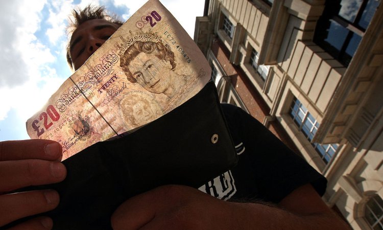 Un uomo a Londra prende una banconota da 20 pound